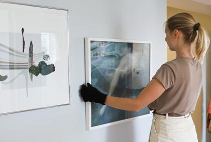 Fulbright Finland alumna Lotta Lemetti hanging her photos on the new Fulbright Finland office wall. 
