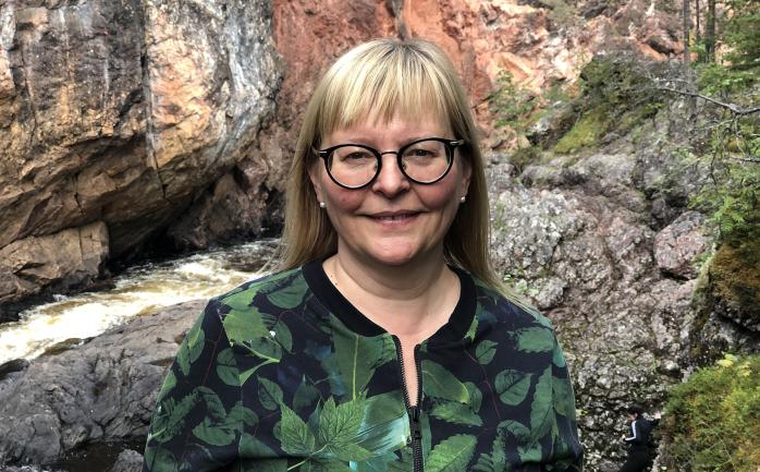 Professor Hanna Lehtimäki photographed in front of a river in a forest
