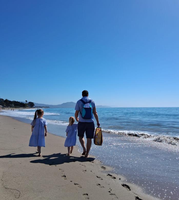 Nuutti Tervo walking on a beach with his two young children. 