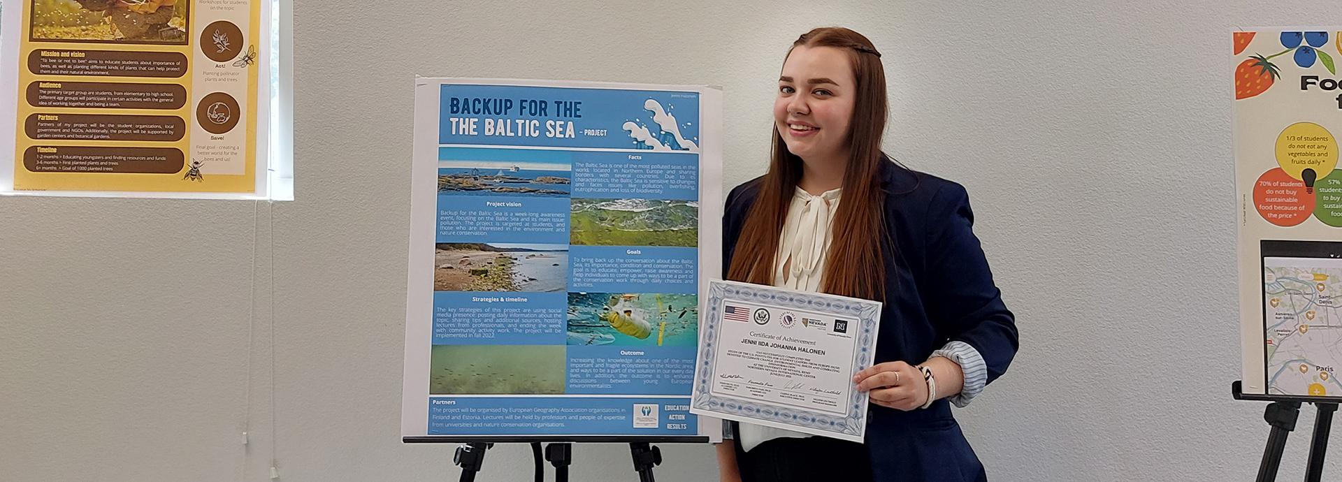Jenni Halonen next to a poster about Baltic Sea.
