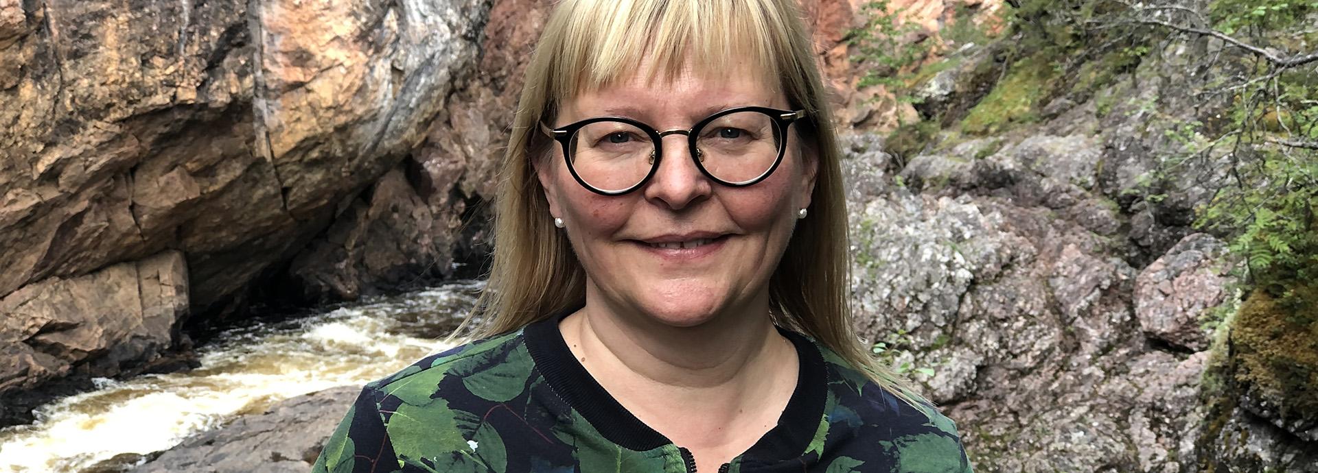 Professor Hanna Lehtimäki photographed in front of a river in a forest