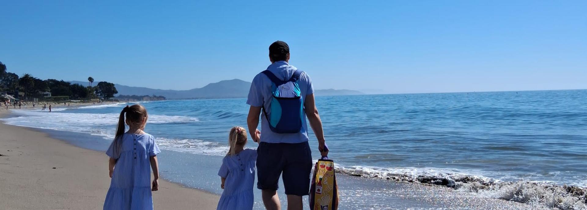 Nuutti Tervo walking on a beach with his two young children. 