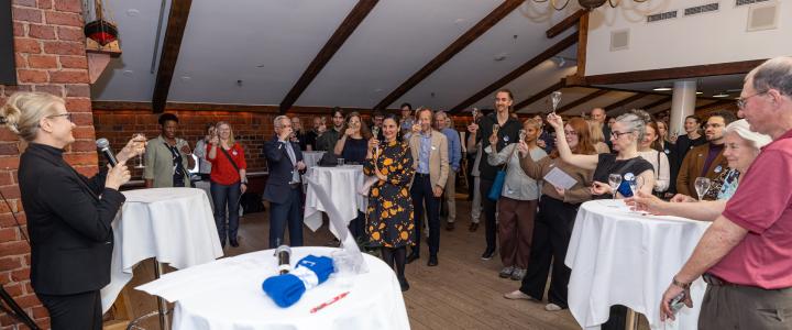 A large group of people smiling and raising a glass in celebration