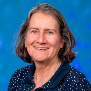 Person with shoulder length hair in front of a bright blue background
