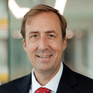 Person in short light hair and black suit smiling at the camera