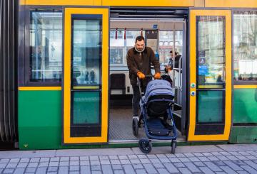 A man with a stroller exiting a tram